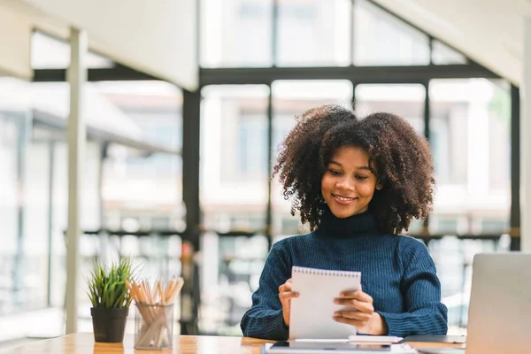 stock image African American businesswoman or accountant with afro hair using a calculator, graphs, and charts to analyze market data, balance sheets, accounts, and net profits