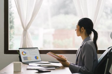 Bir veri grafiğindeki finansal yatırımları, iş ve pazarlama artışını analiz etmek için dizüstü bilgisayar kullanan bir iş kadını veya muhasebeci. Muhasebe, ekonomi ve ticari analiz kavramları