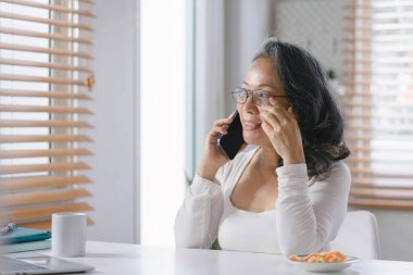 Kıdemli iş kadını danışmanı ev telefonundaki finansal, muhasebe ve yatırım danışmanı konseptlerindeki finansal durumu analiz ediyor ve tartışıyor.