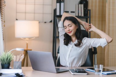 Bir iş kadını ofiste çalışırken dinlenmek için masasına tembelce uzanır.