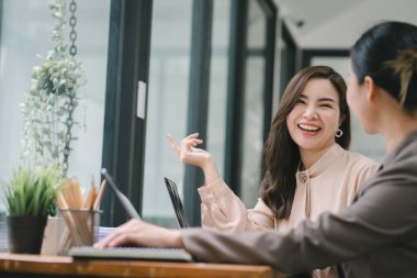 İki işadamı veya bir muhasebeci, istatistiksel bir rapor hazırlamak ve mali verileri bir ofiste tartışmak için dizüstü bilgisayardaki veri tablolarını, grafikleri ve gösterge panelini analiz ediyor.