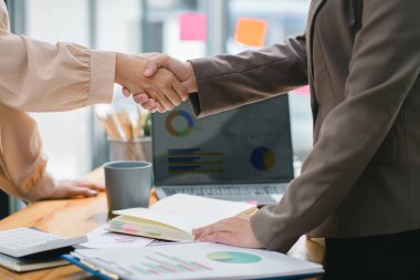 İki işadamı veya bir muhasebeci, istatistiksel bir rapor hazırlamak ve mali verileri bir ofiste tartışmak için dizüstü bilgisayardaki veri tablolarını, grafikleri ve gösterge panelini analiz ediyor.