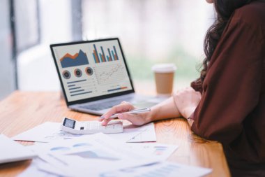 Bir veri grafiğindeki finansal yatırımları, iş ve pazarlama artışını analiz etmek için dizüstü bilgisayar kullanan bir iş kadını veya muhasebeci. Muhasebe, ekonomi ve ticari analiz kavramları