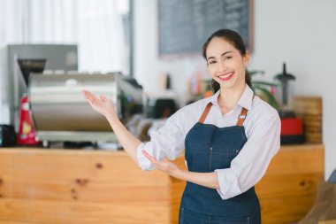Kahve dükkanında müşterileri bekleyen gülümseyen Asyalı bir baristanın portresi. Girişte duran önlüklü, sıradan giysili, başarılı bir iş adamı.