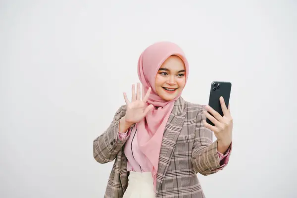 白い背景に隔離されたスマートフォン上の若いイスラム教徒の実業家ピンクのヒジャブのビデオ通話の肖像画 — ストック写真