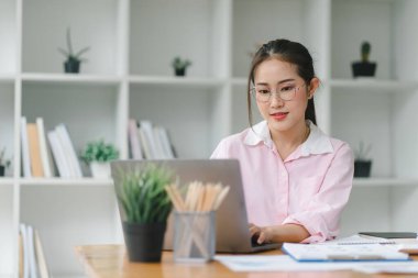 Ofiste dizüstü bilgisayarla çalışırken gülümseyen güzel bir kadın resmi