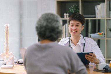 Yaşlı kadın hastaya test sonuçlarını açıklayan genç bir doktor.