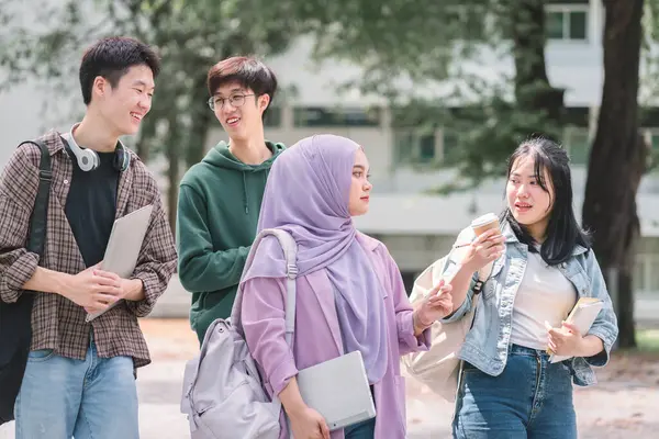 Multi ethnic group of university students walks and talks together outdoors on campus during a break