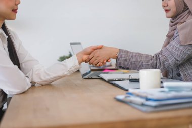 Ofisteki bir toplantıda iki kendine güvenen ve çeşitli iş kadını el sıkışıyor.