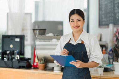 Cheerful small business owners smiling and looking at camera while standing in front of cafe entrance, welcomes guests. Business and entrepreneurs concept