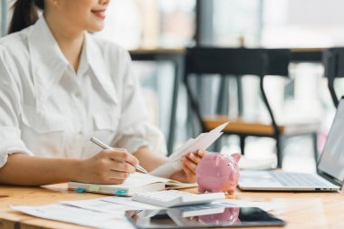Young Asian Female Accountant Engages in Financial Planning with Documents for Budgeting, Savings, and Bill Payments
