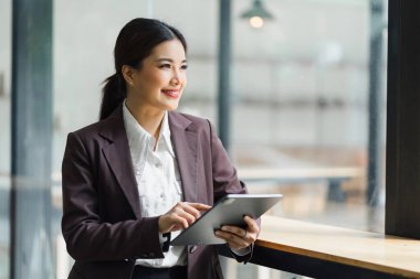 Professional Businesswoman standing and using Digital Tablet at modern office.