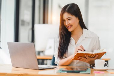 Milenyum Asyalı kadın ofis çalışanı vergi denetim raporları için mali raporlarla ya da kurumsal bir ofisteki mali beyanname için çalışıyor.