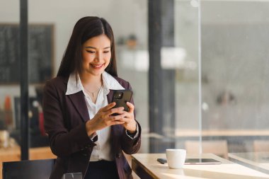 Kahve molası sırasında akıllı telefon kullanan iş kadını.