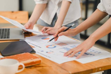 Bir ofiste istatistiksel bir rapor hazırlayıp mali verileri tartışan iki işadamı veya bir pazarlama ekibi, dizüstü bilgisayar ekranında veri tabloları, grafikler ve bir gösterge panelini inceliyor.