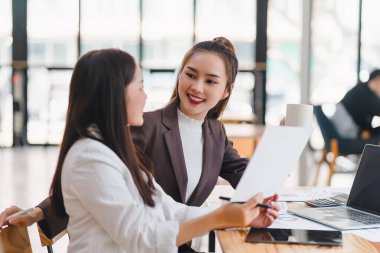 Veri tabloları, grafikleri ve istatistikleri analiz eden iki işadamı veya pazarlama ekibi ve bir istatistiksel rapor hazırlamak ve ofiste mali verileri tartışmak