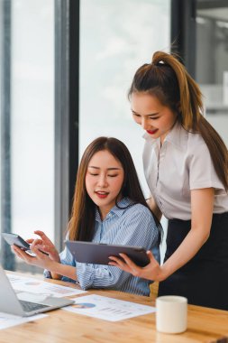 Birlikte çalışan odaklanmış profesyoneller, ofis ortamındaki ahşap bir tabloda basılı veri grafiklerini ve grafiklerini analiz ediyorlar..