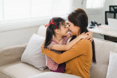 Sevgi dolu bir anne, küçük kızını sıcak bir oturma odasında kucaklıyor.