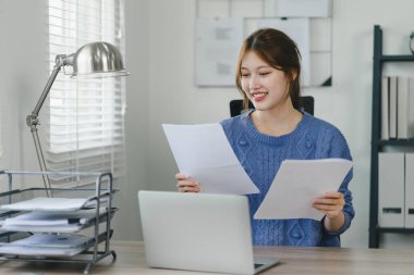 Evde dizüstü bilgisayar ve belgelerle çalışan genç bir iş kadını. İş hayatı dengesi kavramı