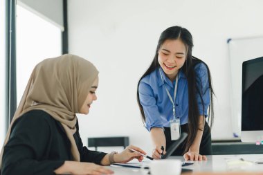 İki profesyonel kadın finansal verileri ve pazarlama stratejilerini tartışıyor ve analiz ediyor, şirket kârlarını artırmak için sunuyor ve beyin fırtınası yapıyor