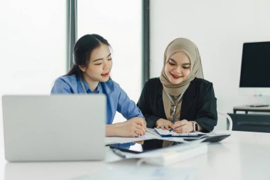 Dizüstü bilgisayarda çalışırken gülümseyen çeşitli iş adamları.