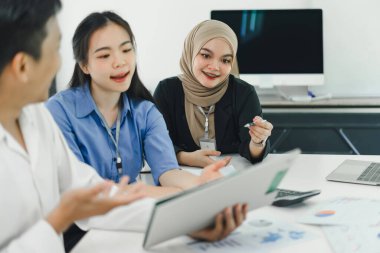 Genç insanlar finansal verileri ve pazarlama stratejilerini tartışıyor ve analiz ediyor, şirket kârlarını artırmak için sunuyor ve beyin fırtınası yapıyor