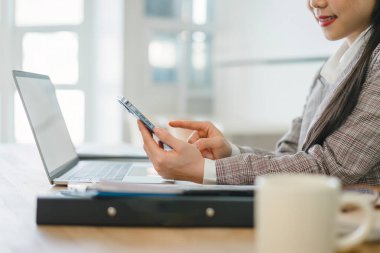 Bilgisayarda çalışan iş kadını ve parlak ofiste çalışan akıllı telefon.