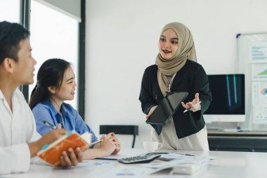 Genç insanlar finansal verileri ve pazarlama stratejilerini tartışıyor ve analiz ediyor, şirket kârlarını artırmak için sunuyor ve beyin fırtınası yapıyor