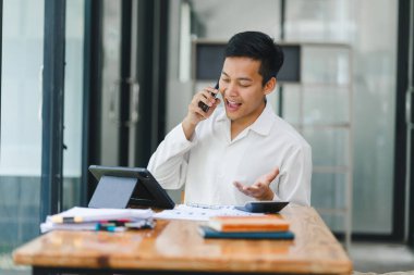 Parlak ofiste tablet üzerinde çalışan genç adam.