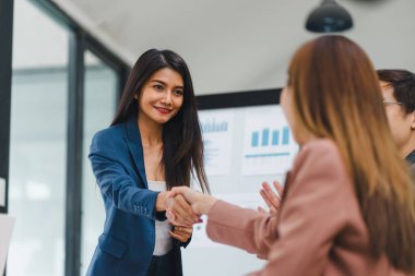 Başarılı iş kadını, modern ofiste sunumdan sonra meslektaşıyla tokalaşıyor..