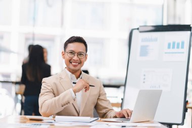 Ofisinde dizüstü bilgisayarı olan takım elbiseli genç bir iş adamının portresi.
