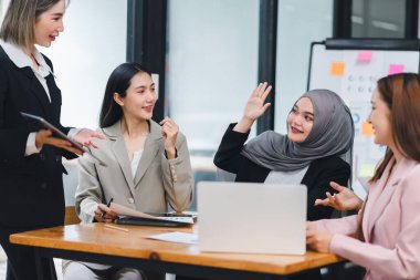 Asyalı iş kadınları fikirleri tartışıyor ve ofiste başarıyı tartışıyorlar. Ofiste çalışan iş adamları.