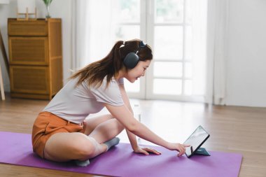 Asyalı bir kadın tablet bilgisayarda spor yapıyor ve online ders veriyor..