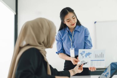 Modern ofiste toplantı sırasında veri tablolarını inceleyen ve tartışan iki iş kadını