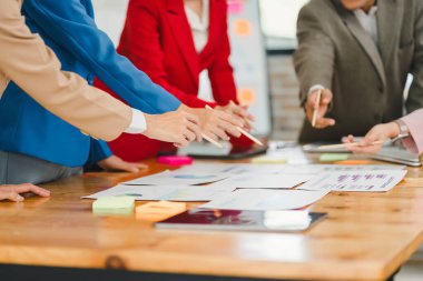 Çeşitli iş adamları toplantı sırasında işbirliği yapar ve raporları analiz eder, modern ofiste takım çalışması ve stratejik planlamayı vurgular