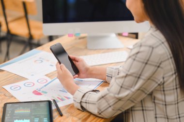 İşadamı, bir hesap makinesi ile bütçeyi hesaplıyor ve ahşap bir masadaki belgelerin finansal çizelge ve grafiklerini analiz ediyor..