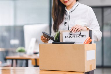 Modern ofiste işten çıkarılma uyarısı aldıktan sonra personel kişisel eşyalarını karton kutuya koyuyor.