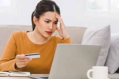 İnternetten kredi kartı ekstrelerine bakan endişeli bir kadın, mali durumu idare ediyor ve evdeki mali stresle uğraşıyor.