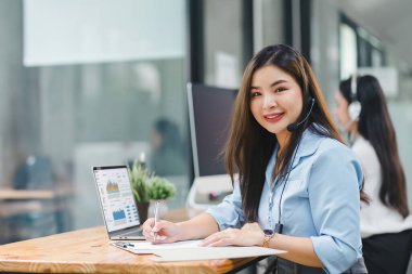 Modern ofiste veri analizi için dizüstü bilgisayar kullanan, kulaklık takan bir operatör.