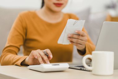 Evde hesap makinesi ve dizüstü bilgisayar kullanarak harcamaları hesaplayan odaklı kadın, finans yönetimi
