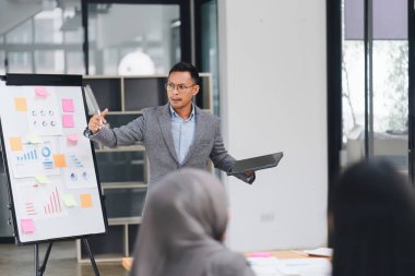 Modern ofiste toplantı sırasında veri grafiklerini ve grafiklerini sunan ve tartışan profesyonel iş ekibi