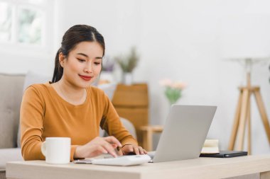 Güzel Asyalı kadın, faturaları incelerken hesap makinesi ve dizüstü bilgisayar kullanarak evde finansman yönetiyor. Finans bütçesi, yatırım muhasebe veya sigorta vergisi kavramı