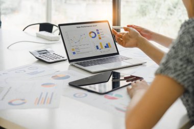 İki işadamı veya bir muhasebeci, istatistiksel bir rapor hazırlamak ve mali verileri bir ofiste tartışmak için dizüstü bilgisayardaki veri tablolarını, grafikleri ve gösterge panelini analiz ediyor.