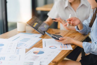 Konsol ekranında iş verilerini analiz eden ve modern bir ofiste finansal grafik ve grafikleri tartışan iki profesyonel.