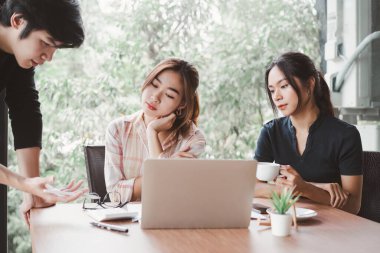 Modern ofiste birlikte çalışırken iletişim kuran ve fikirleri paylaşan bir grup genç iş adamı.