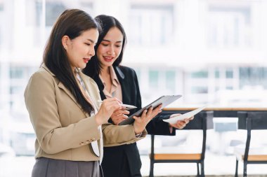 Konsol ekranında iş verilerini analiz eden ve modern bir ofiste finansal grafik ve grafikleri tartışan iki profesyonel.