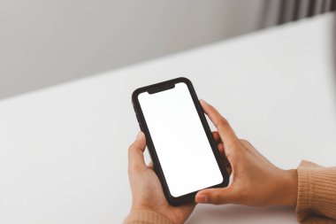 Eller beyaz ekranlı akıllı telefonu tutuyor. Özelleştirmeye hazır. Düz beyaz bir arkaplanda.