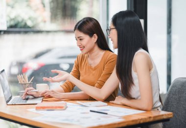 Yeni projeyi tartışan iki bayan meslektaşım, ofiste dizüstü bilgisayar kullanan iş kadınları.
