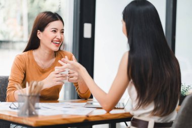 İki genç Asyalı iş kadını, ofiste planlama ve mali istatistikleri, yatırım piyasasını analiz etmek üzere yeni bir girişim projesini tartışıyor.