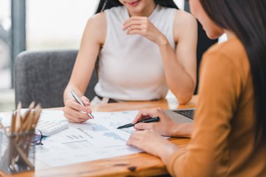 İki işadamı veya bir muhasebeci ekibi, istatistiksel bir rapor hazırlamak ve bir ofiste mali verileri tartışmak için veri grafikleri ve grafikleri analiz etmektedir.
